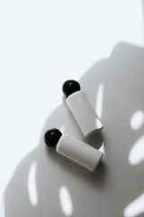 Two white empty plastic bottles on a white background with a shadow of a tropical leaf. Shampoo, shower gel or balsam concept