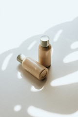 Two empty plastic bottles on a white background with a shadow of a tropical leaf. Shampoo, shower gel or balsam concept