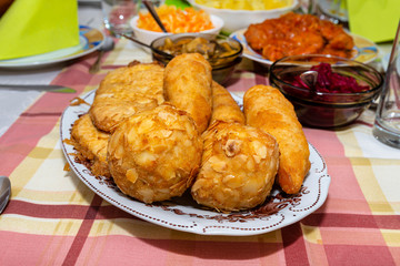 A pile of fried, stuffed Polish croquettes lying on a decorated table, visible mushrooms and beets.
