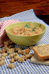 home-made soup made of vegetables in a green bowl with pieces of dry bread