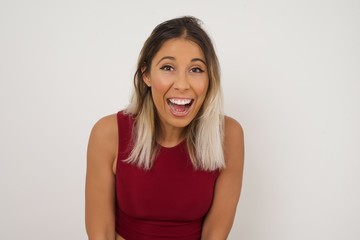 Emotive young beautiful woman wears casual clothes, happy and excited to celebrate anniversary. Happy young woman has good mood stands against gray wall.