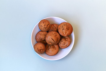 Cupcakes with raisins and lemon in the blue plate on the blue background. Copy space. Place for text and design. Top view. Flat lay. Quarantine life.