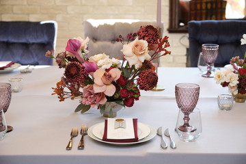 Luxury cozy autumn wedding table decoration in the restaurant. Fresh and dried flowers, roses,...