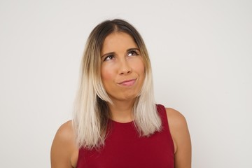 Fototapeta premium Gloomy, wondering young woman looking up with lips together, being upset thinking about something important, keeps hands down.