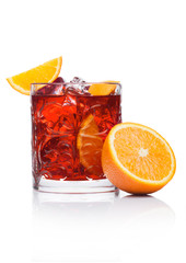 Negroni Cocktail in crystal glass with ice cubes and orange slices on white background with reflection.