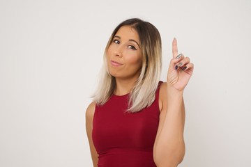 Fototapeta premium Young caucasian woman standing against gray wall showing and pointing up with fingers number one while smiling confident and happy.