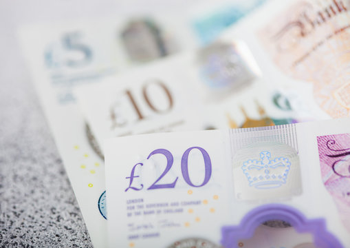 New twenty, ten and five pounds banknotes close up on light background.