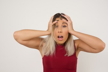 Obraz premium Horrible, stress, shock. Portrait of young emotional crazy woman clasping head in hands. Human emotions, facial expression concept. Trendy colors. Front view