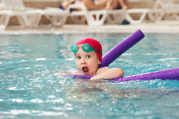 Little girl learning to swim in a pool