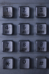 Close up of a dirty public telephone metal keypad. Macro view of the buttons and digits of a public...