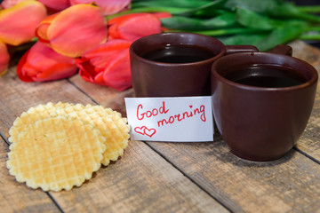 Breakfast. A cup of coffee with a good morning note and tulips. Coffee and waffles for breakfast.