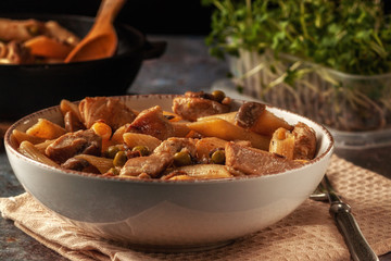 Homemade pasta with green peas, chicken and sauce on a dark background