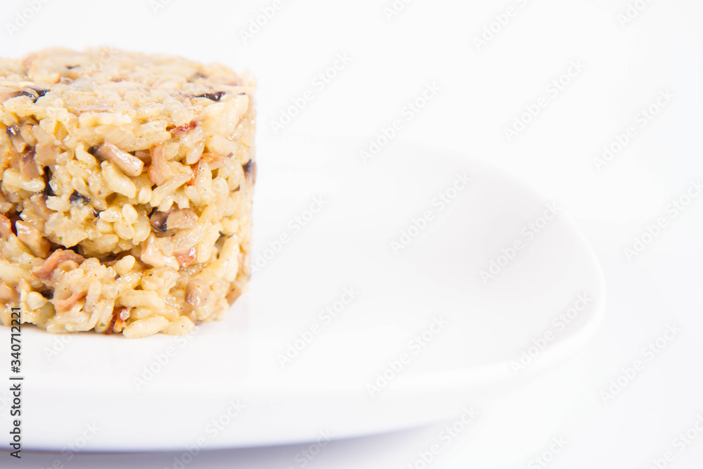 Sticker risotto with button mushroom and bacon on a plate on a white background