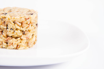 Risotto with button mushroom and bacon on a plate on a white background