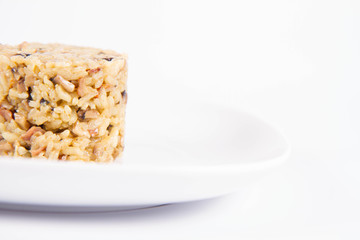 Risotto with button mushroom and bacon on a plate on a white background