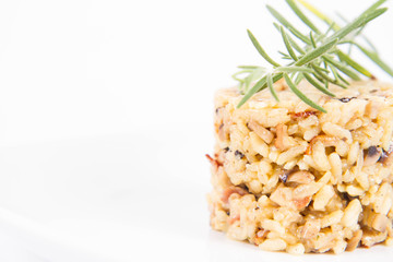 Risotto with button mushroom and bacon decorated with rosemary twig on a plate on a white background