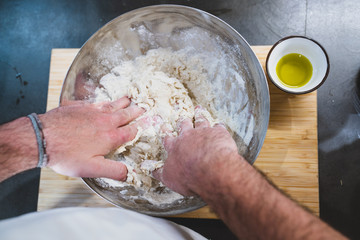 young man mixing water, flour, yeast with hands. he want to prepare pizza and bread.