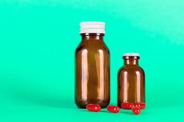 Big and small medicines glass bottles with red capsules