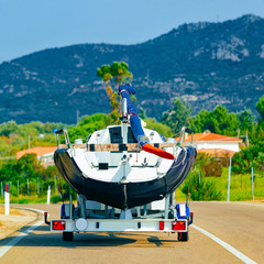 Car with yacht or motor boat on road in Sardinia reflex