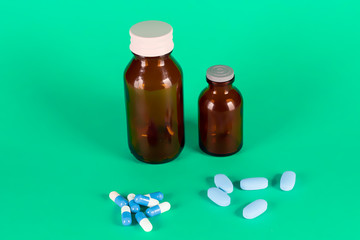 Big and small medicines glass bottles with blue capsules and blue vitamins
