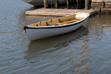 Small white rowboat moored by dock and stone wall, horizontal aspect