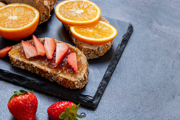 Healthy fruity breakfast, bread with jam and slice of orange and strawberry.