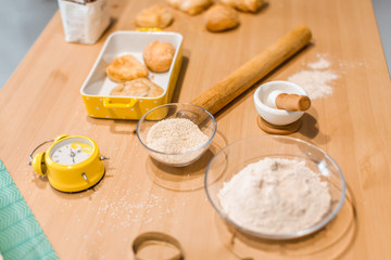 Ingredients for baking, rolling pin, flour in bowls, sugar, vanilla, molds and ceramic forms for baking, towel