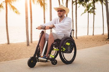Disabled man in a wheelchair with electric scooter on the beach