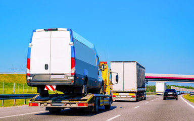 Tow truck transporter carrying mini van in Road in Slovenia reflex