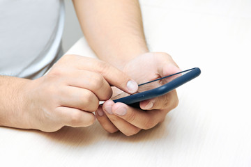A young man is holding and using a black phone