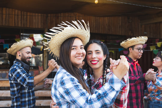 Festa Junina in Brazil, known as brazilian June Party. Loving couple together in traditional plaid clothes dancing at Arraial Party. Fun, happy moments.
