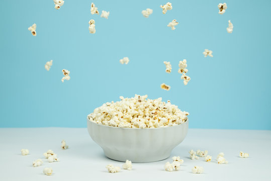 Dreamy image of popcorn falling from the sky over a bowl full of popcorn.