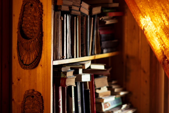 Wicker bast shoes hanging on a wooden bookshelf with old books
