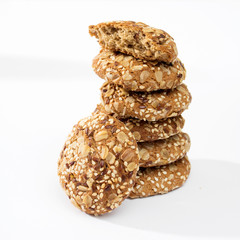The oatmeal cookies sprinkled with sesame seeds and almonds on a table against a gray wall in the kitchen.
