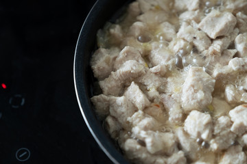 Sliced ​​stewed chicken in a pan, close-up.
