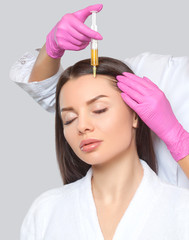 Cosmetologist does prp therapy against hair loss and anti-dandruff of a beautiful woman in a beauty...