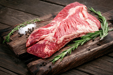 Raw hanging tender or onglet steak of beef on wooden Board with rosemary and thyme on wooden...