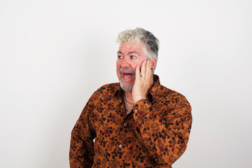 Amazement - man excited looking to the side hand on face. Surprised happy young man looking sideways in excitement. Caucasian male model on gray background.