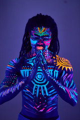 Fototapeta premium young african man blur with ultraviolet body art, fluorescent prints glows on neon light, isolated in studio. mystery, luminescence, fluorescence, ethnic body art