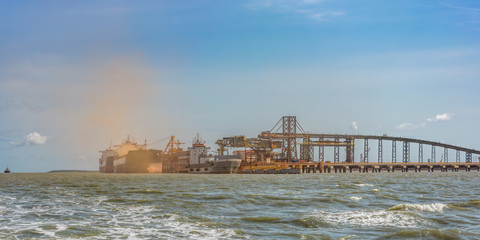 Loading bulk carrier ships with bauxite aluminum ore at Kamsar port, Guinea.