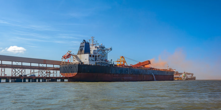 Loading bulk carrier ship with bauxite aluminum ore at Kamsar port, Guinea.