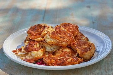Small baked pizza style rolls made from puff pastry and filled with fresh tomato sauce, mozzarella and fresh herbs like oregano, served on vintage white plate. Snack to be combined with white vine.