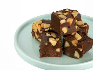Homemade macadamia nut fudge on a light jade green plate against a white background.