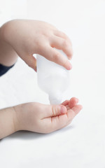 Children's hands and disinfectant, on a white background.
