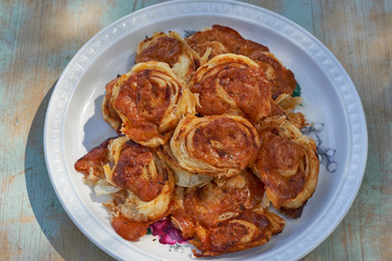 Close up Picture of vintage porcelain plate full of baked homemade italian style pizza scrolls made from puff pastry and filled with mozzarella cheese and tomato sauce with herbs. Snack for vine.