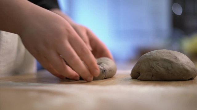 Female hands in black gloves kneading dough on table. Beautiful white flour. Side view.