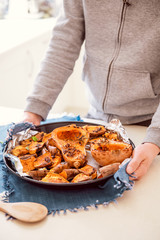 Male hands putting baking sheet with roasted grilled orange pumpkin butternut squash halfs and sweet potato slides with herbs on blue napkin. Vegetarian and vegan food diet. Healthy eating. Vertical.