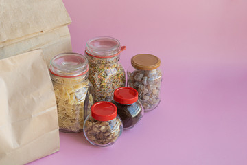 Different food with paper bags on a pink background, donation concept