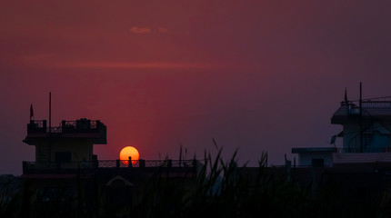 Obraz premium Silhouetted little girl playing on the terrace against the setting sun. People are not allowed to go out due to recent lockdown imposed amid concerns over coronavirus outbreak. selective focus