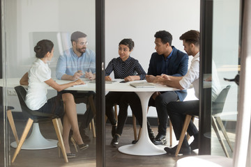 Diverse business people gather in boardroom negotiating planning future partnership view through...